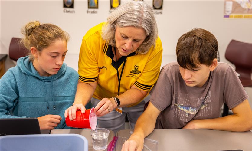 A teacher helps two students